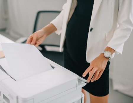 partial view of pregnant businesswoman using printer in office